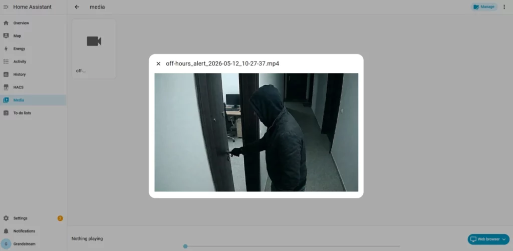 Record - Documentation Center Hooded figure in a dark jacket opening a door in a dim hallway; security footage still.